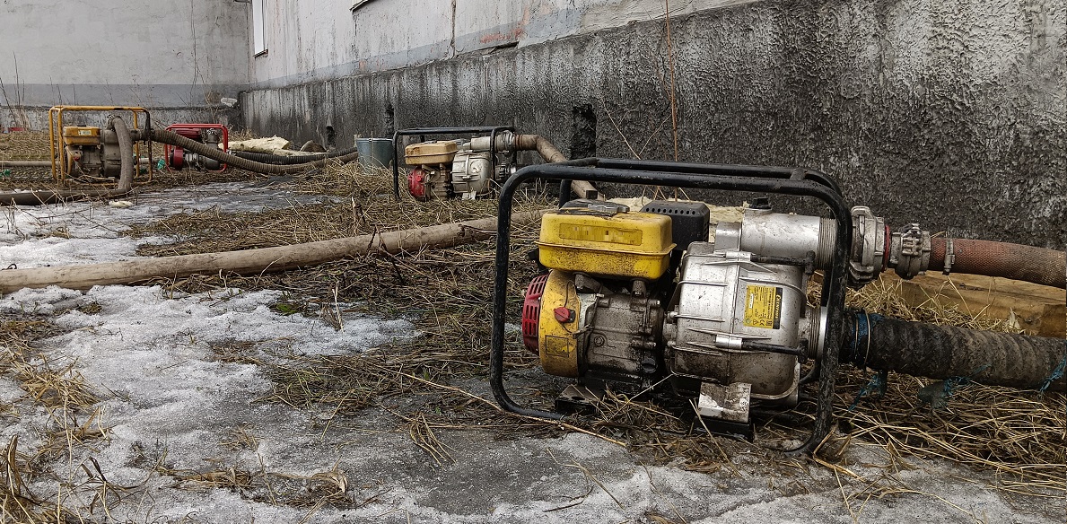 Откачка мотопомпами талой воды из подвала дома в Краснокаменске